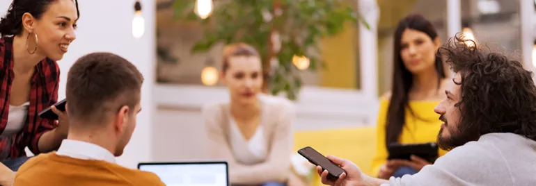 Persone discutono in un ufficio moderno con piante e luci soffuse.