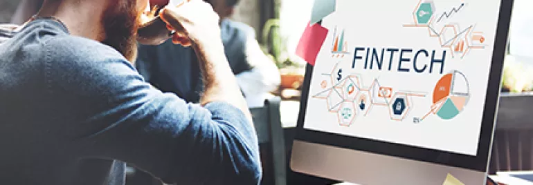 Persona lavora al computer con schermo che mostra 'FINTECH'.