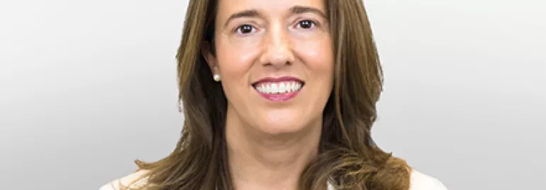 Persona con capelli castani sorridente in giacca bianca.