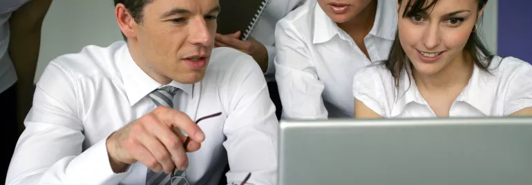 Gruppo di persone in ufficio che osservano uno schermo di laptop.