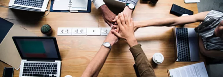Persone riunite intorno a un tavolo con computer portatili.