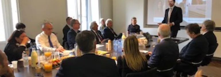 Riunione aziendale in una sala con una presentazione proiettata.