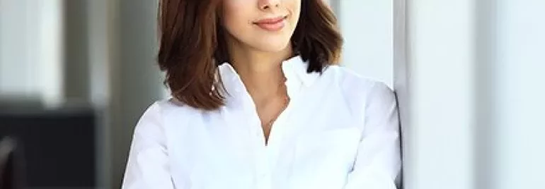 Persona in camicia bianca guarda fuori dalla finestra.