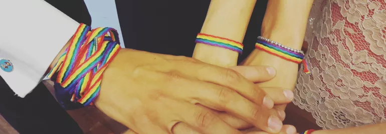 Mani unite con braccialetti arcobaleno.