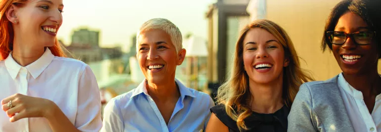 Gruppo di persone sorridenti con caffè all'aperto.