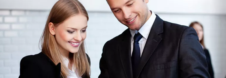 Due persone in abiti eleganti guardano un tablet con interesse.
