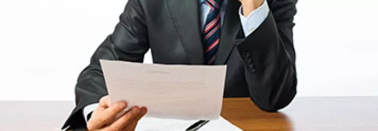 Persona in abito formale legge un documento.