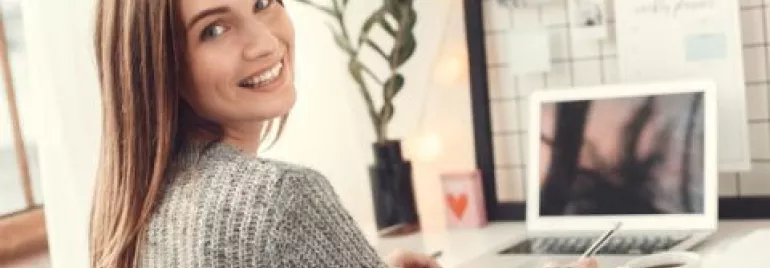 Persona sorridente al lavoro a un computer portatile.