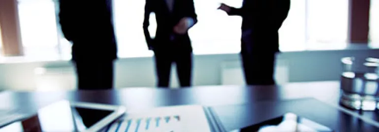 Ufficio con persone che discutono e grafici su un tavolo.