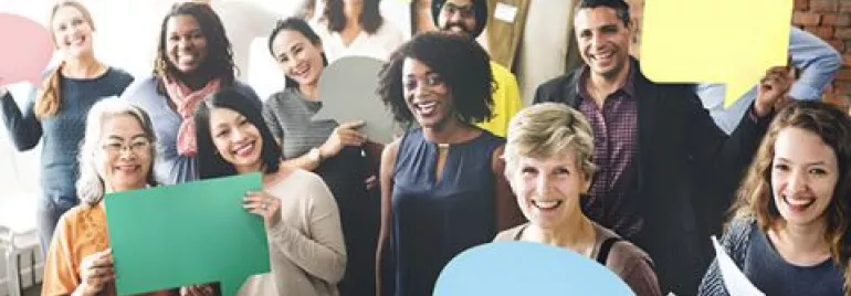 Persone che tengono cartelli colorati e sorridono.
