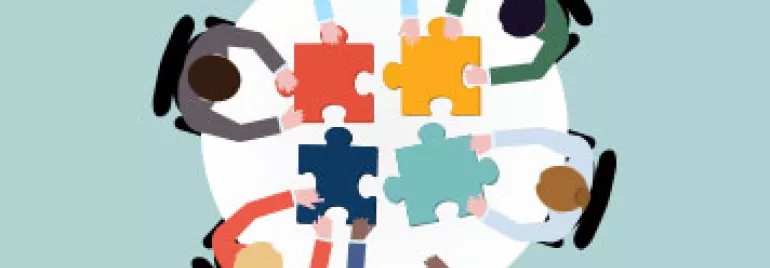 Gruppo di persone sedute attorno a un tavolo con pezzi di puzzle.