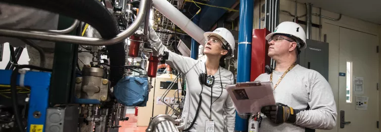 Due lavoratori in una fabbrica osservano un macchinario complesso.