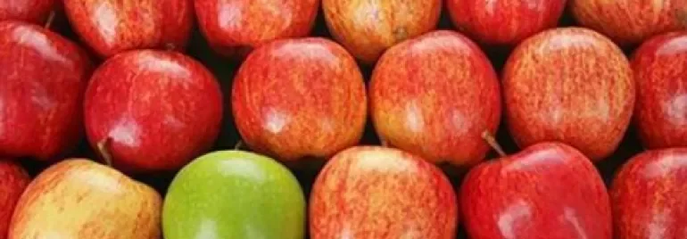 Mele rosse con una mela verde al centro.