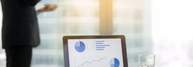 Ufficio moderno con laptop e grafici su schermo.