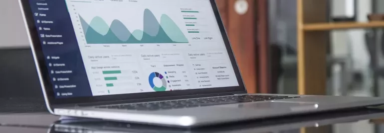 Computer portatile su un tavolo con grafici e dati sullo schermo.