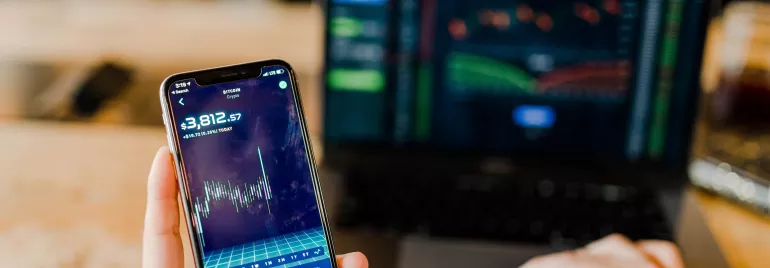 Smartphone e laptop con grafici di mercato.