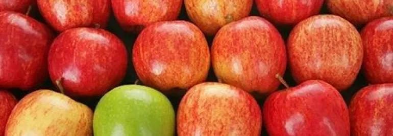 Mele rosse con una mela verde al centro.