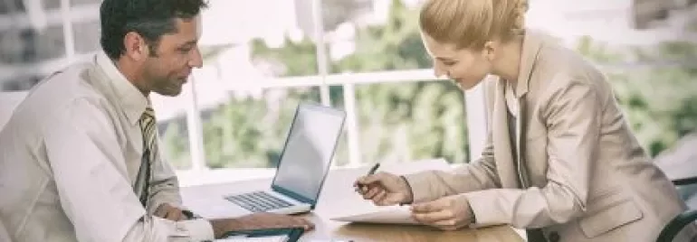 Due persone discutono in ufficio con un computer portatile.
