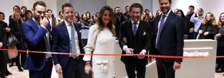 Inaugurazione di un nuovo ufficio con persone sorridenti che tagliano un nastro rosso.