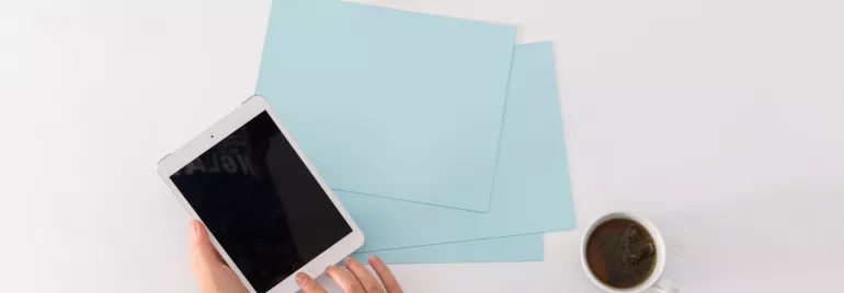 Due persone con tazze di tè e un tablet su un tavolo.