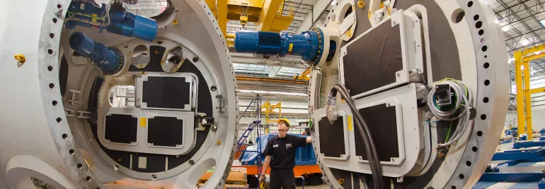 Lavoratore controlla grandi macchine industriali in un impianto.