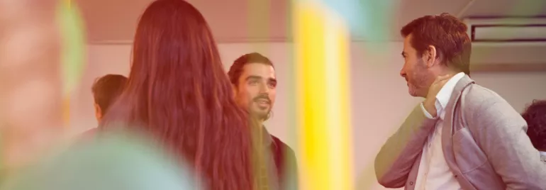 Persone che conversano in un ufficio con piante in primo piano.