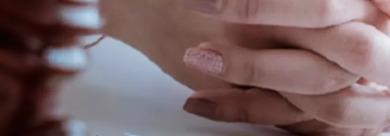 Mani intrecciate su una scrivania con un martelletto e documenti.