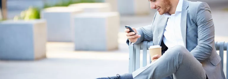 Persona seduta su una panchina usa il telefono.