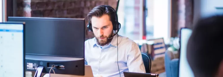 Persona al lavoro con cuffie e computer in un ufficio moderno.