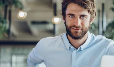 Persona sorridente in ufficio con laptop.